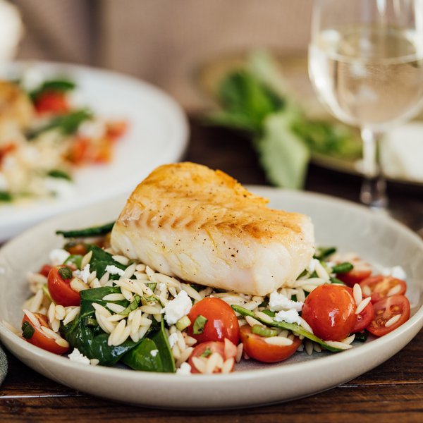 Poisson avec vinaigrette sur un lit d’orzo, d'épinards et feta